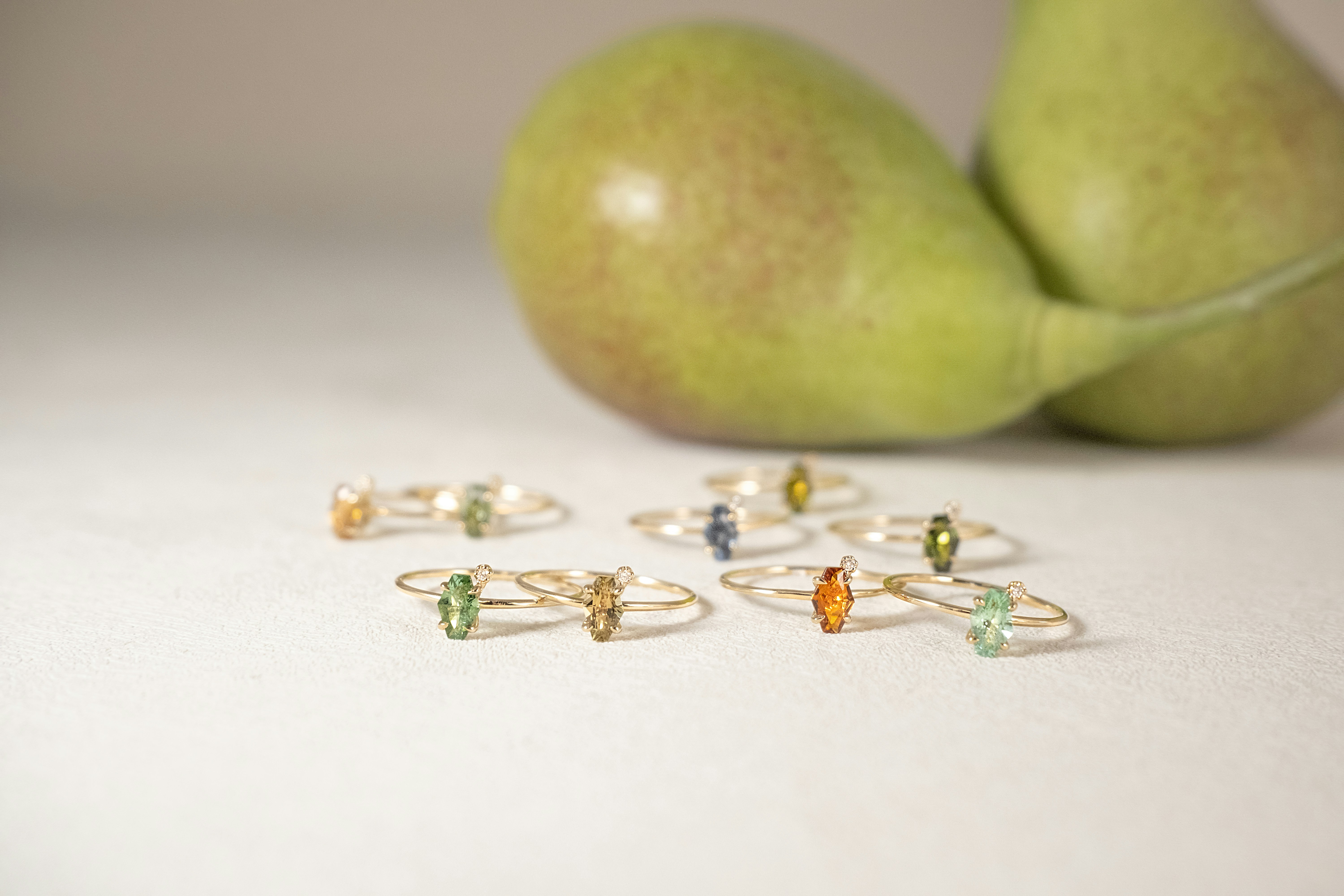 Ringe mit Edelsteinen stehen neben Birnen.