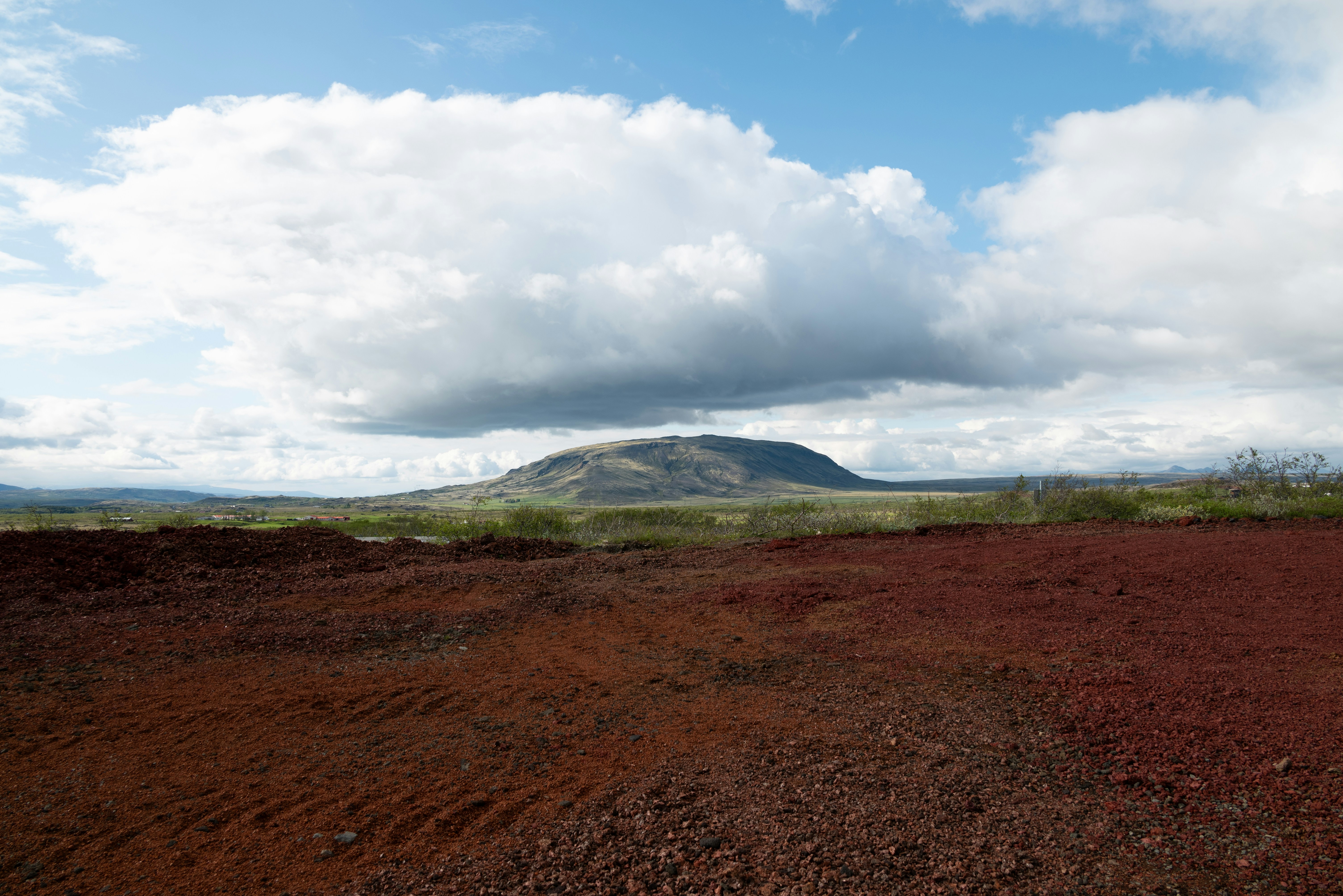 A wide landscape features a mountain and cloudy sky.