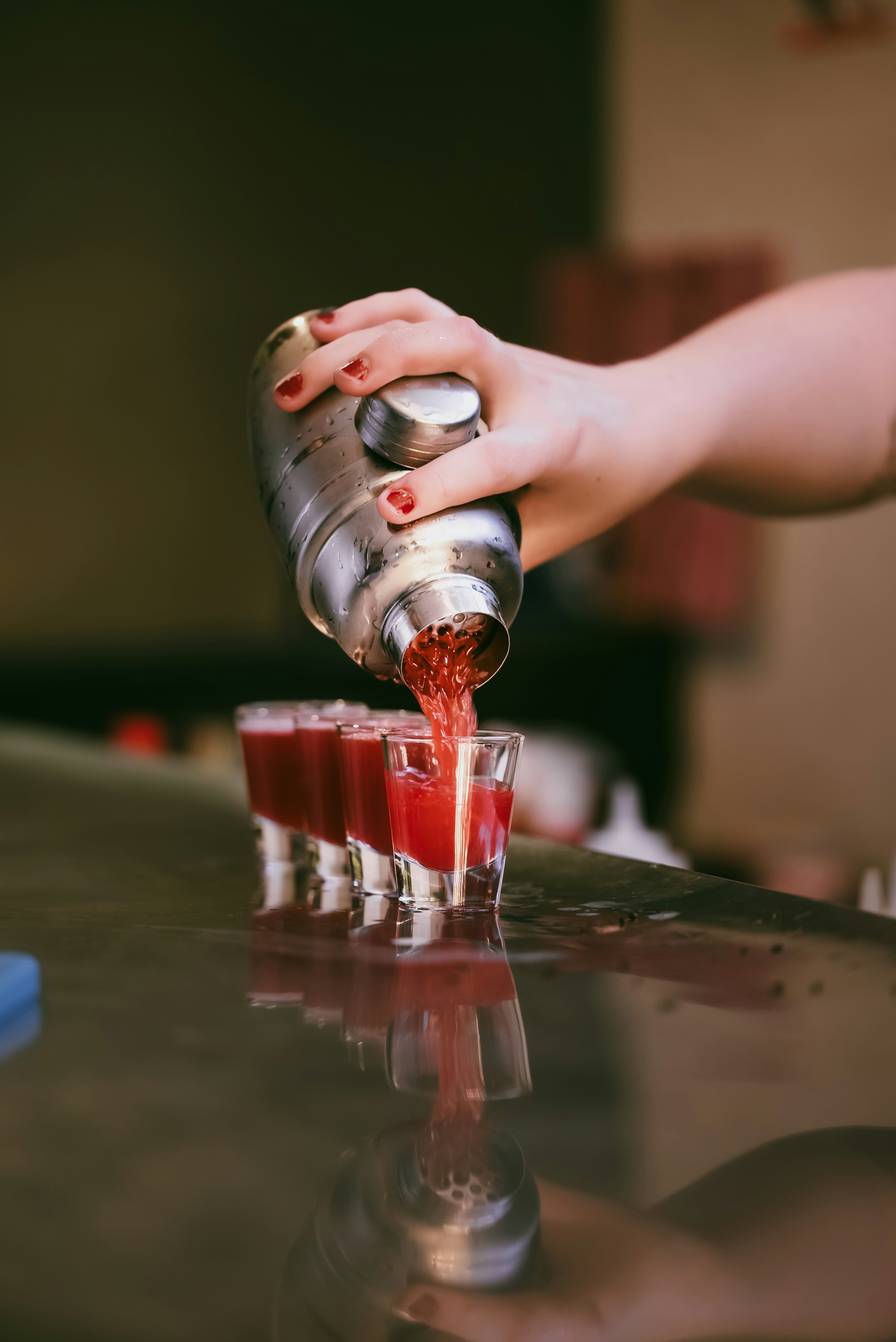 Someone is pouring shots from a cocktail shaker.
