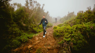 People hike along a muddy trail in the forest.
