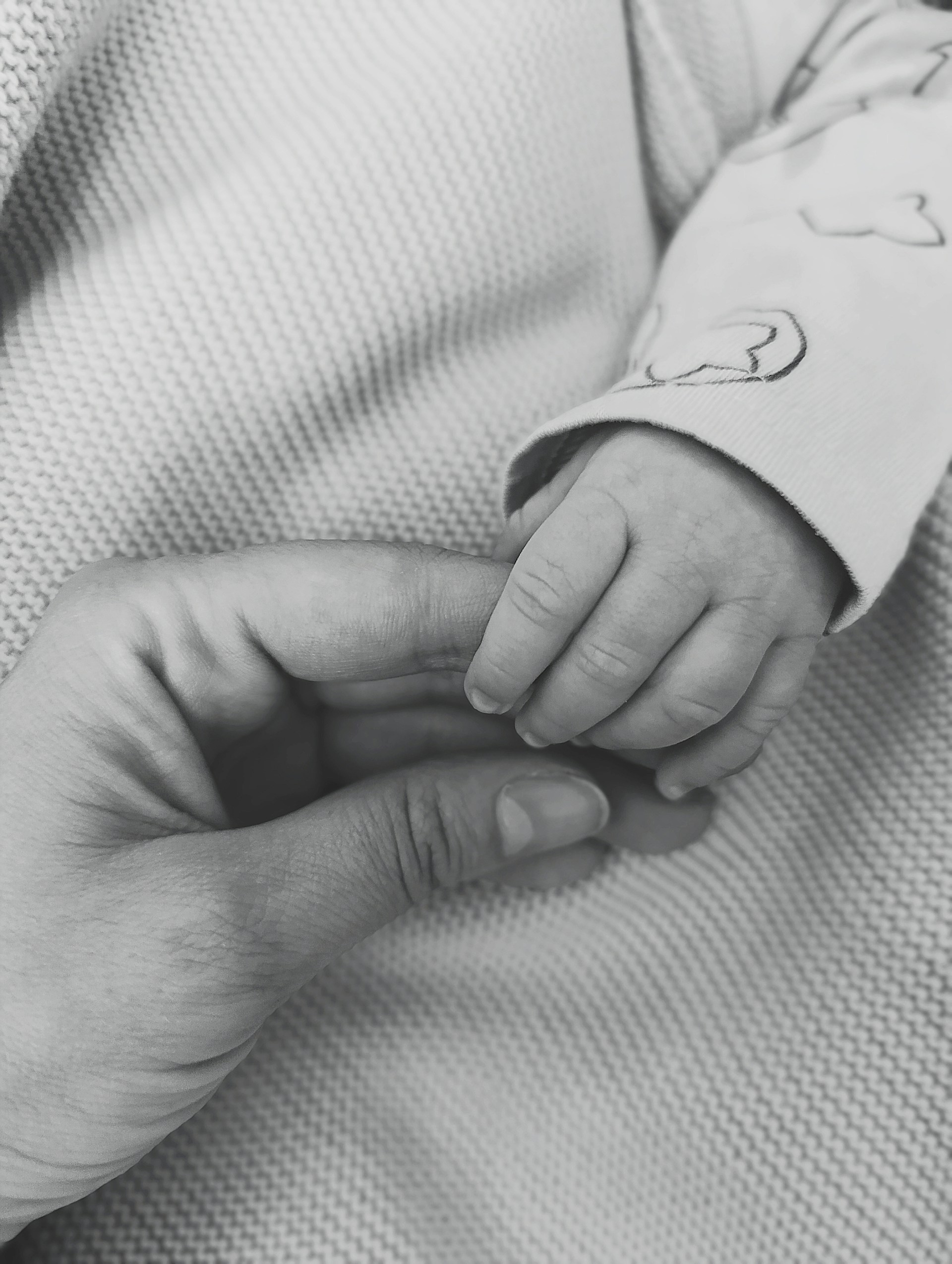 A parent holds their baby's hand.