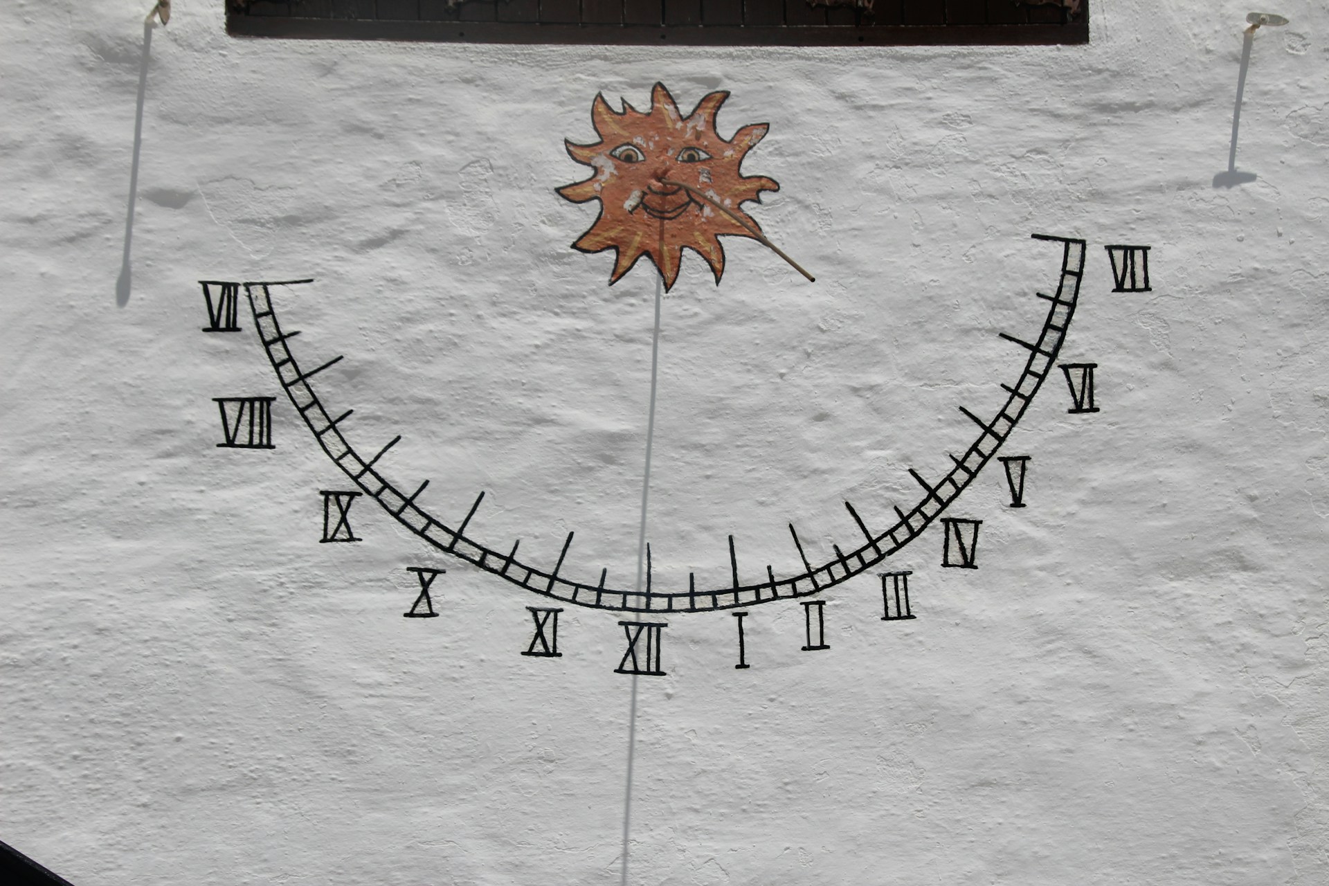 A sundial adorns the textured, white wall.