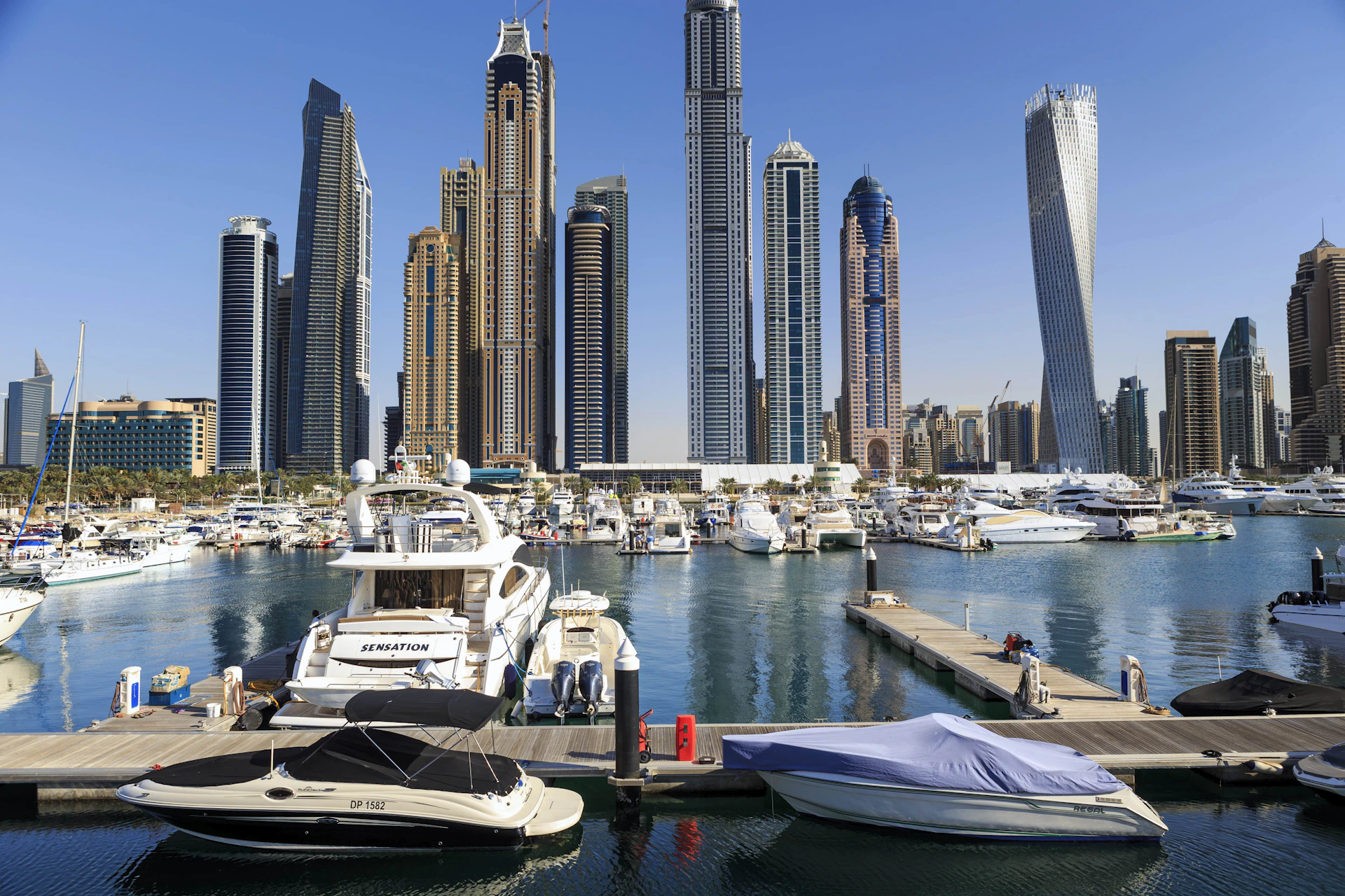 Boats and skyscrapers line a beautiful harbor.