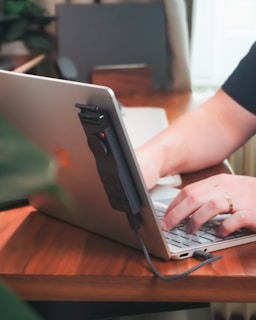 Someone is using a laptop with a device.