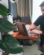 Man works on laptop at a tidy desk.