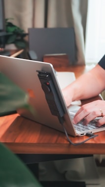 Person works on a laptop with a connected device.