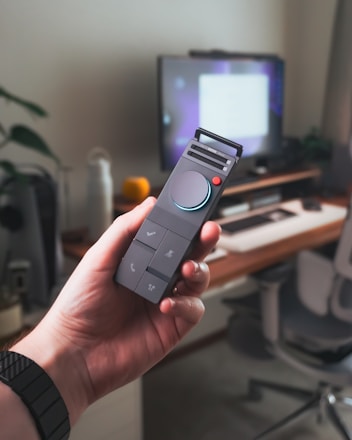A hand holds a modern remote control.