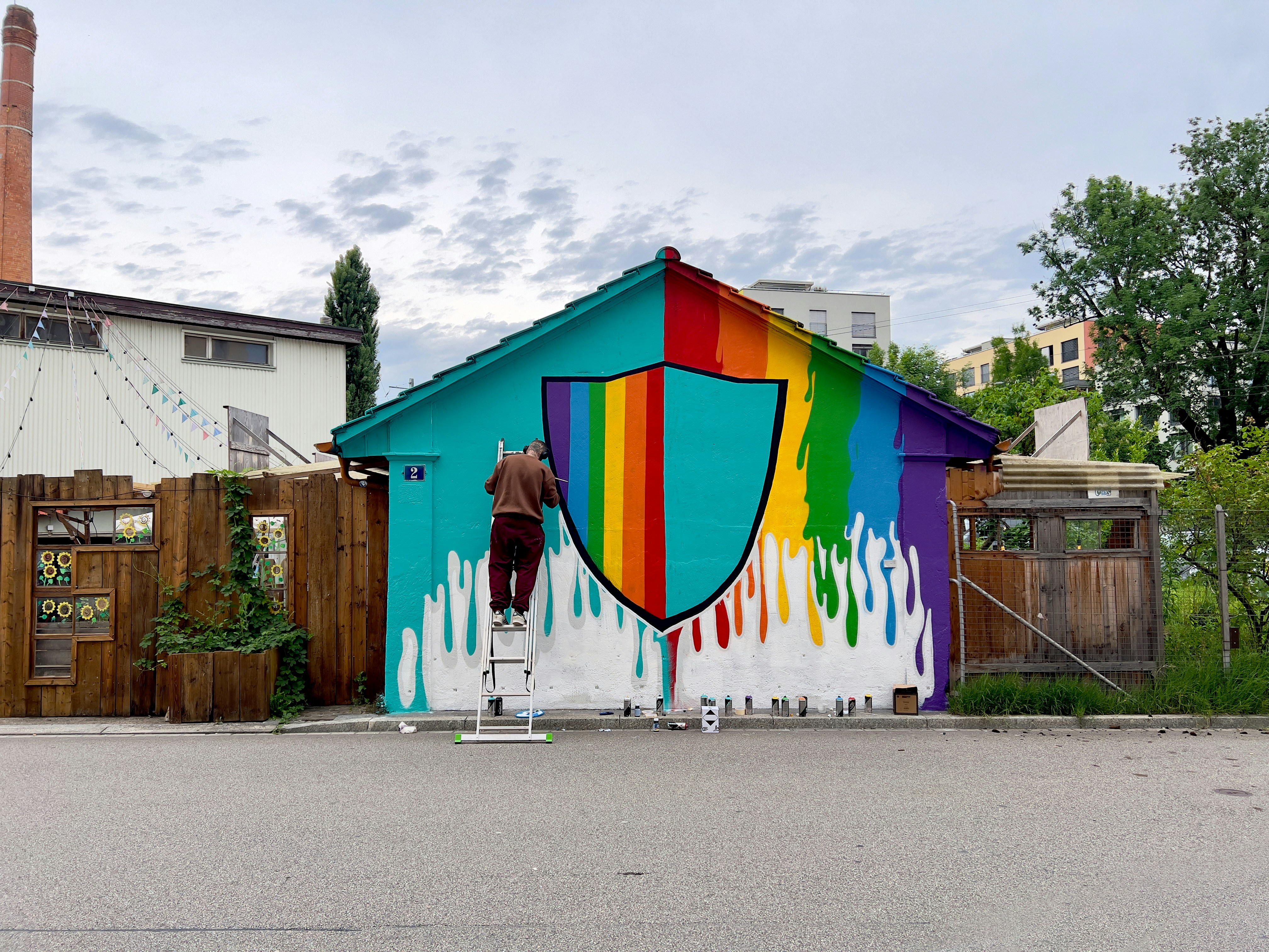 A person paints a colorful mural on a small building