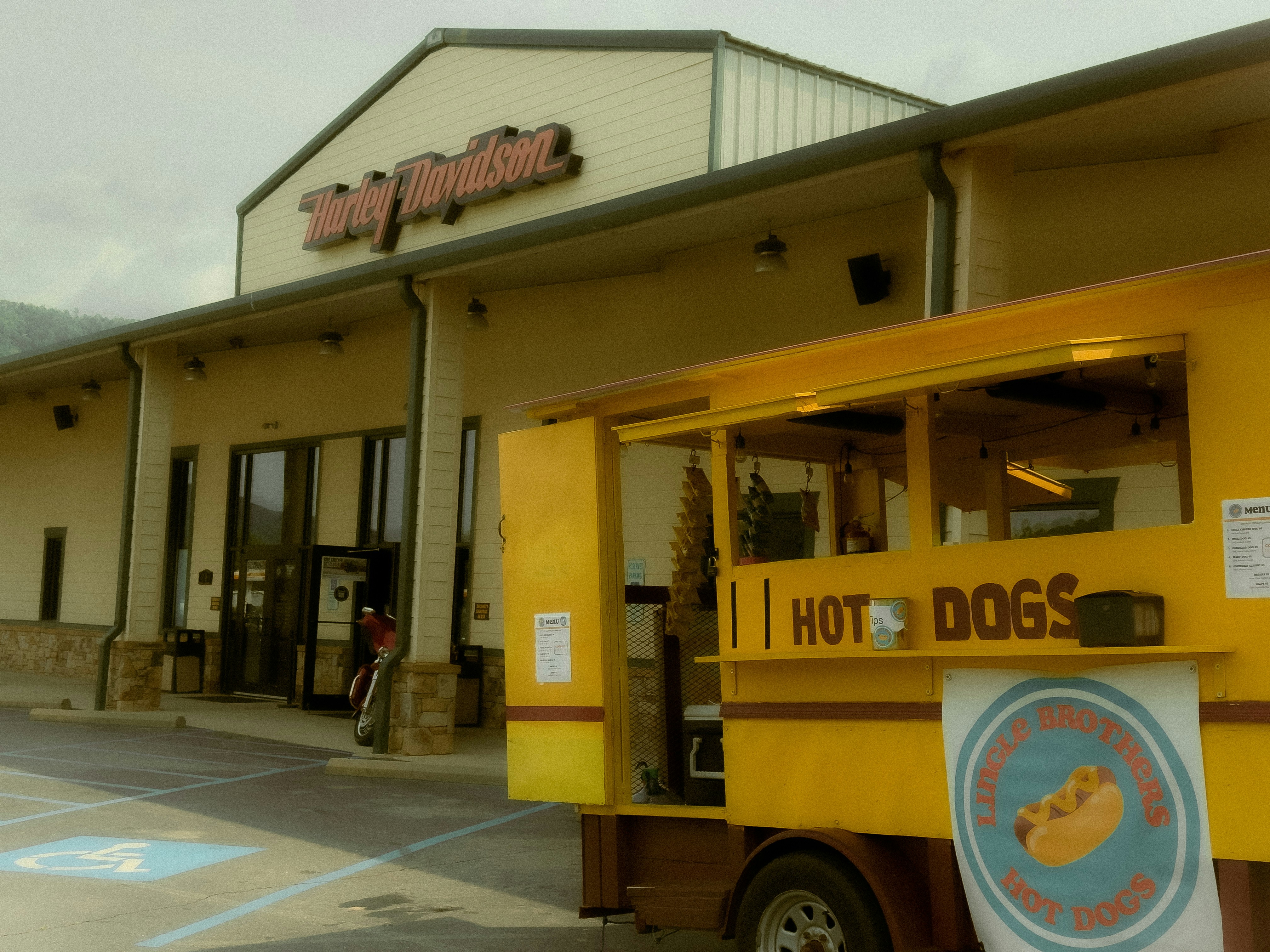 Hot dog cart outside a building with a sign