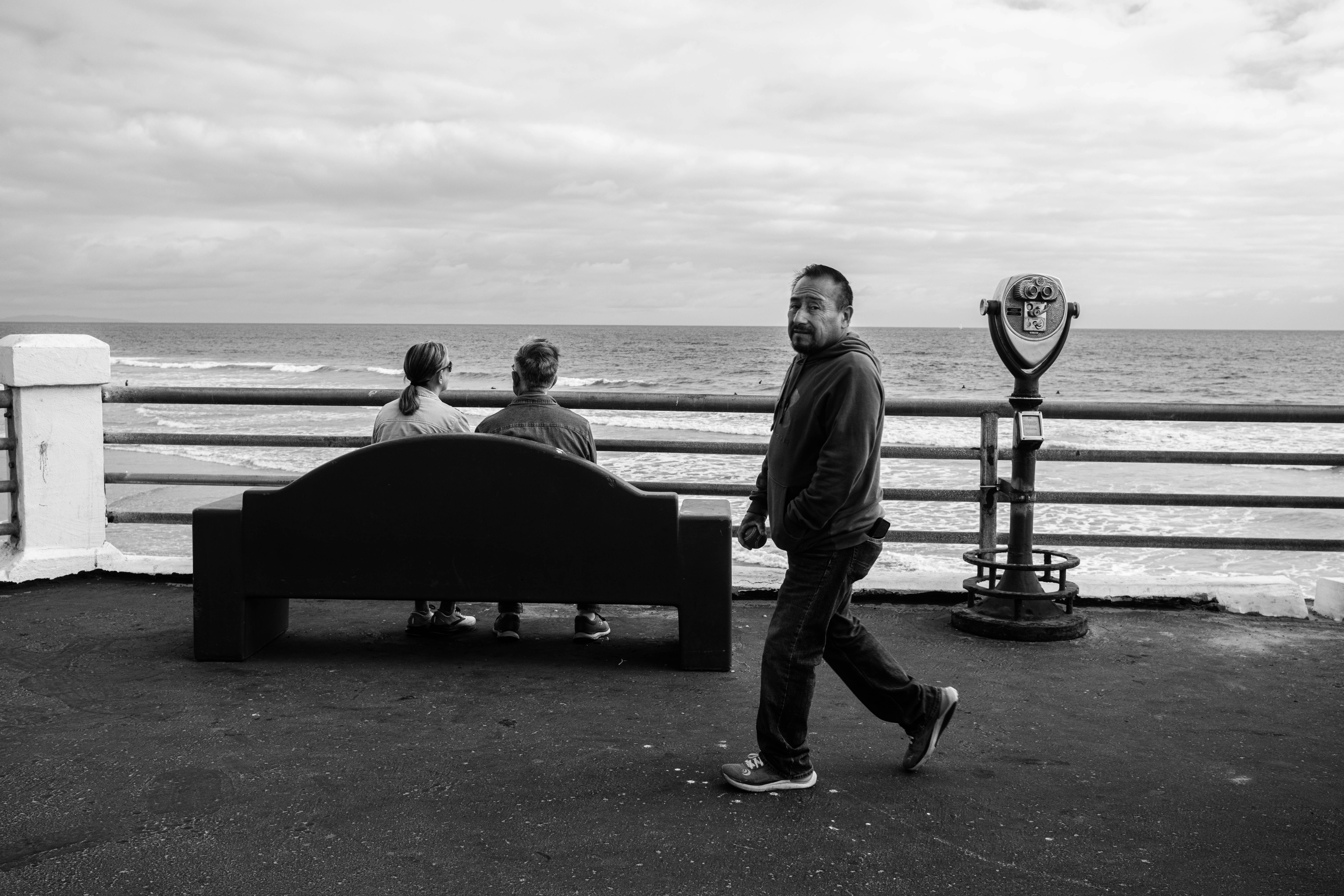 Man walks past others enjoying ocean views.