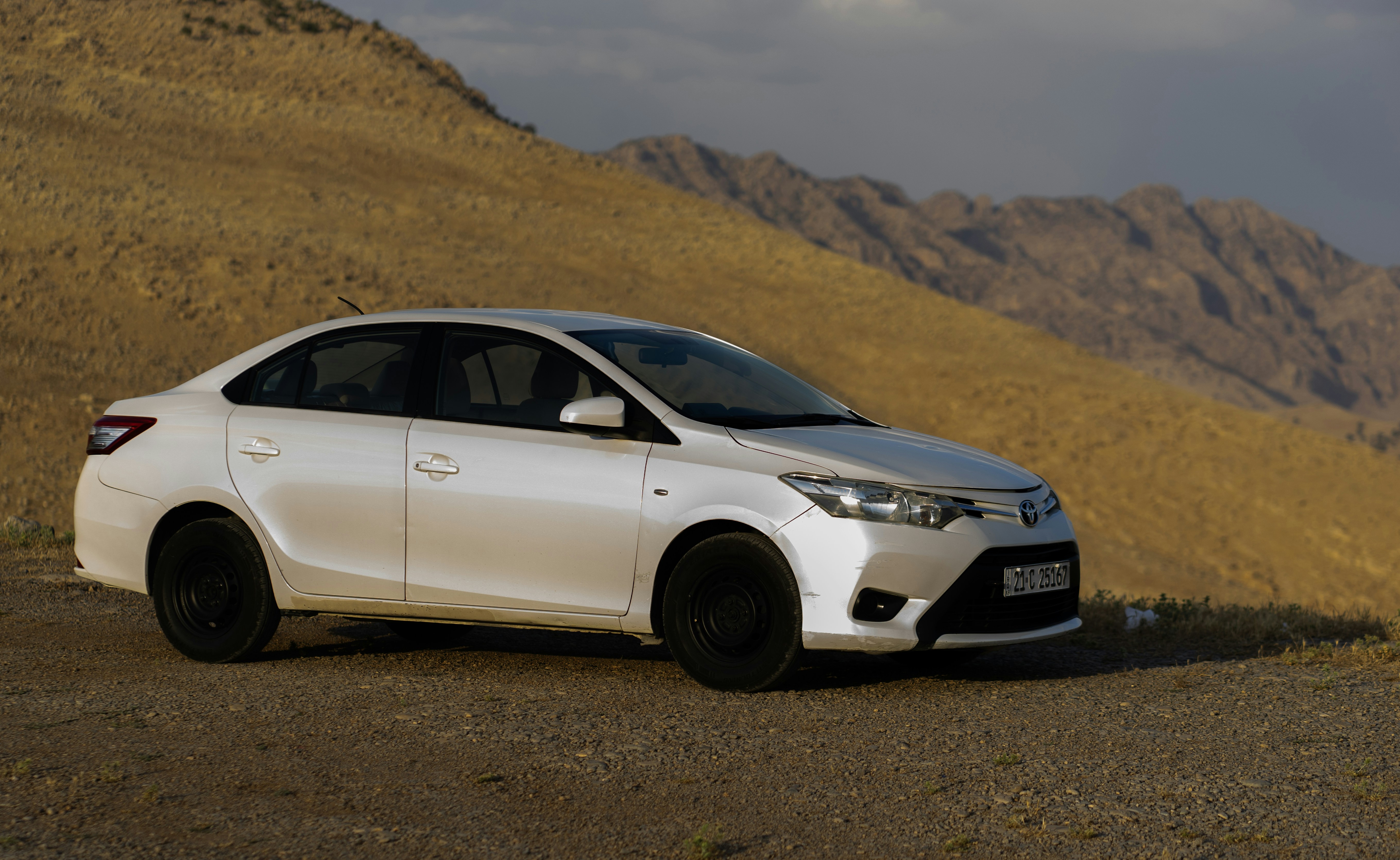 A white car sits on a desert landscape.