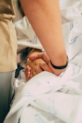 A hand holds another's for comfort.