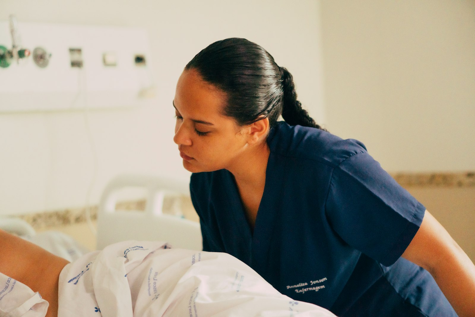A nurse in scrubs attending to a patient on a hospital floor.