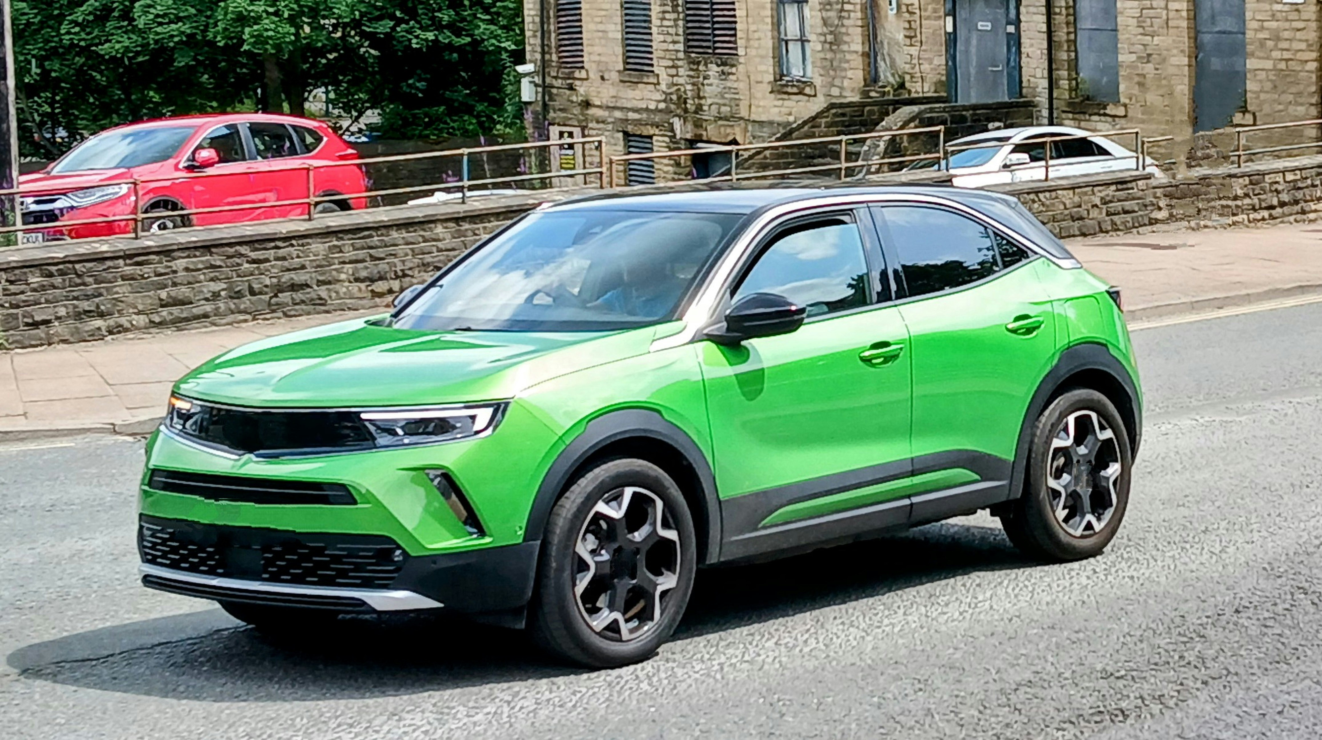 A green suv drives on a street.