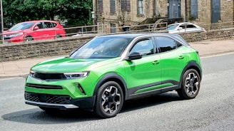 A green suv drives on a street.