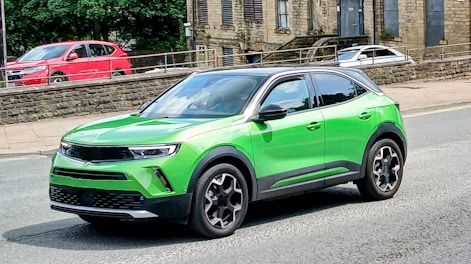 A green suv drives on a street.