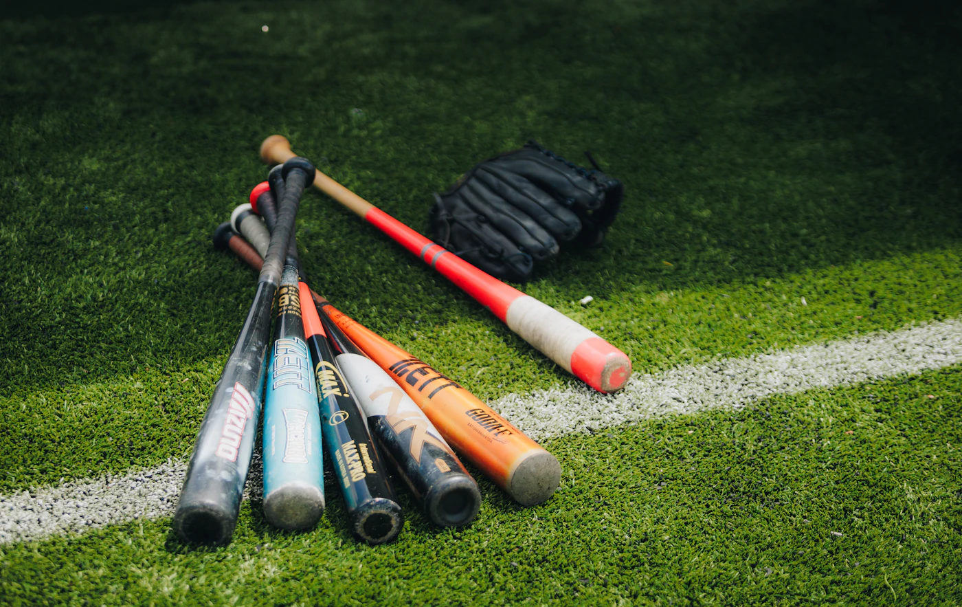 baseball bats and glove on grass