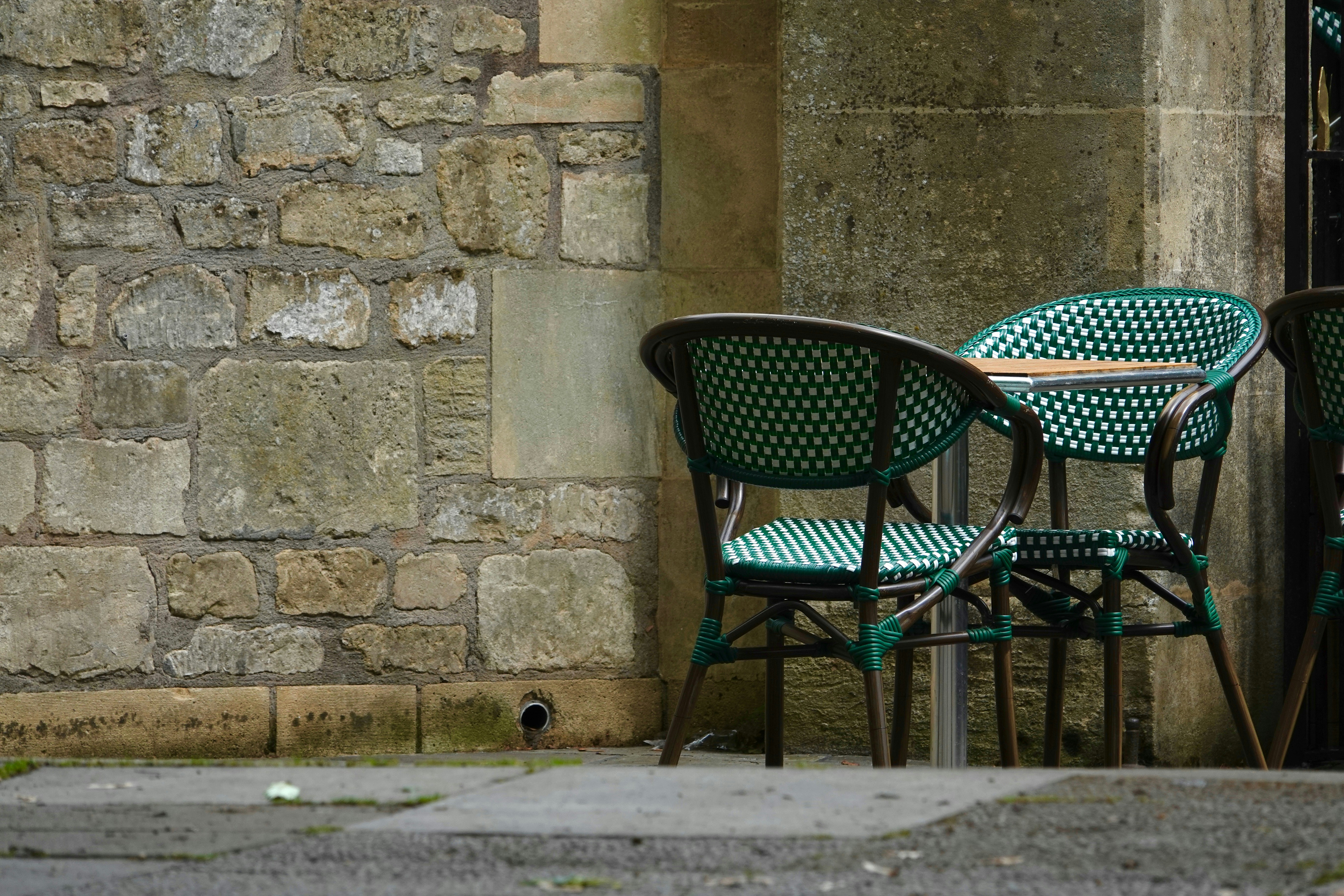 Outdoor chairs sit near a stone wall.