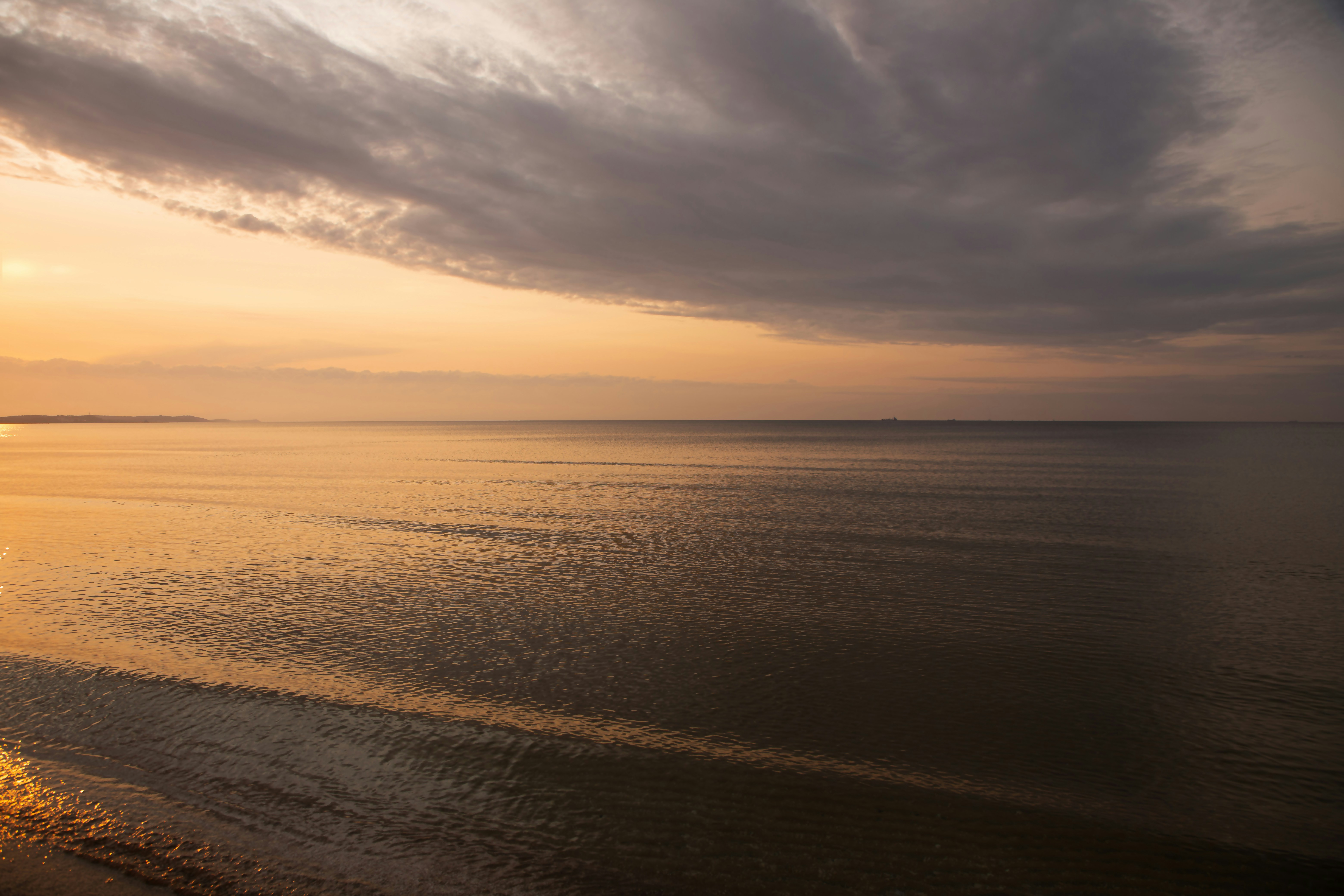 Calm ocean reflects the sunset sky.