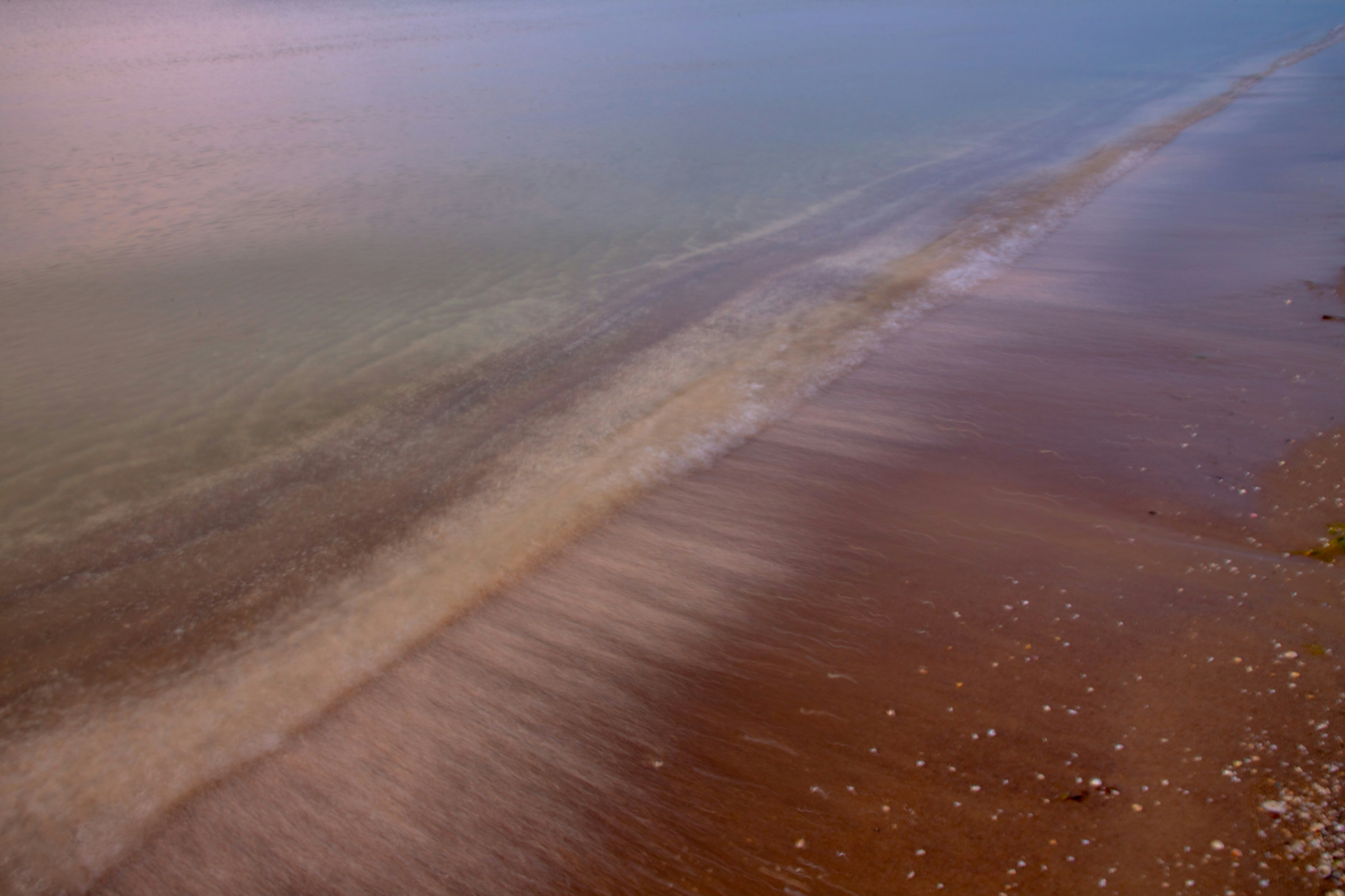 Water gently washes over a sandy shore.
