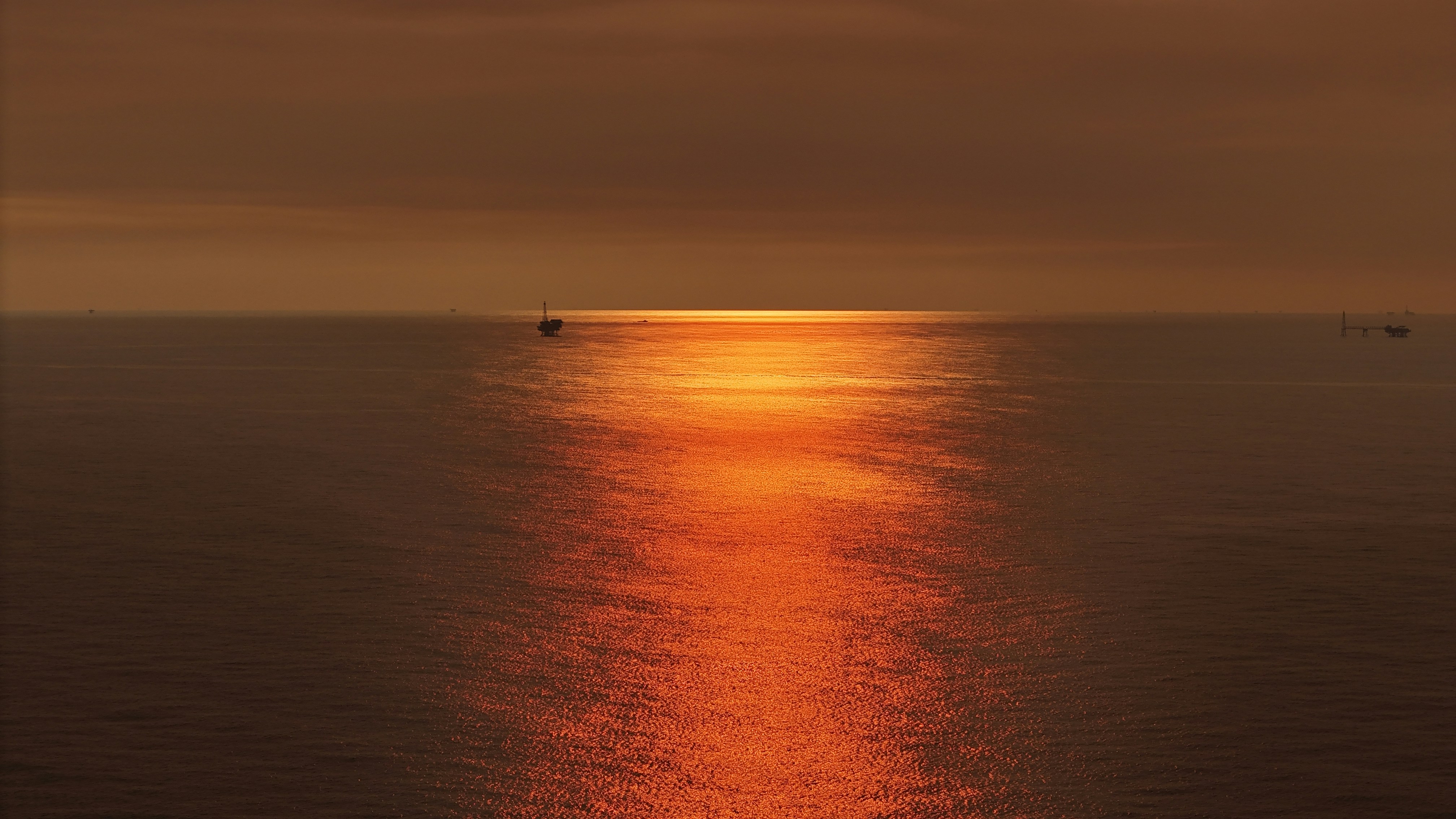 Sun reflects on a calm, orange ocean.