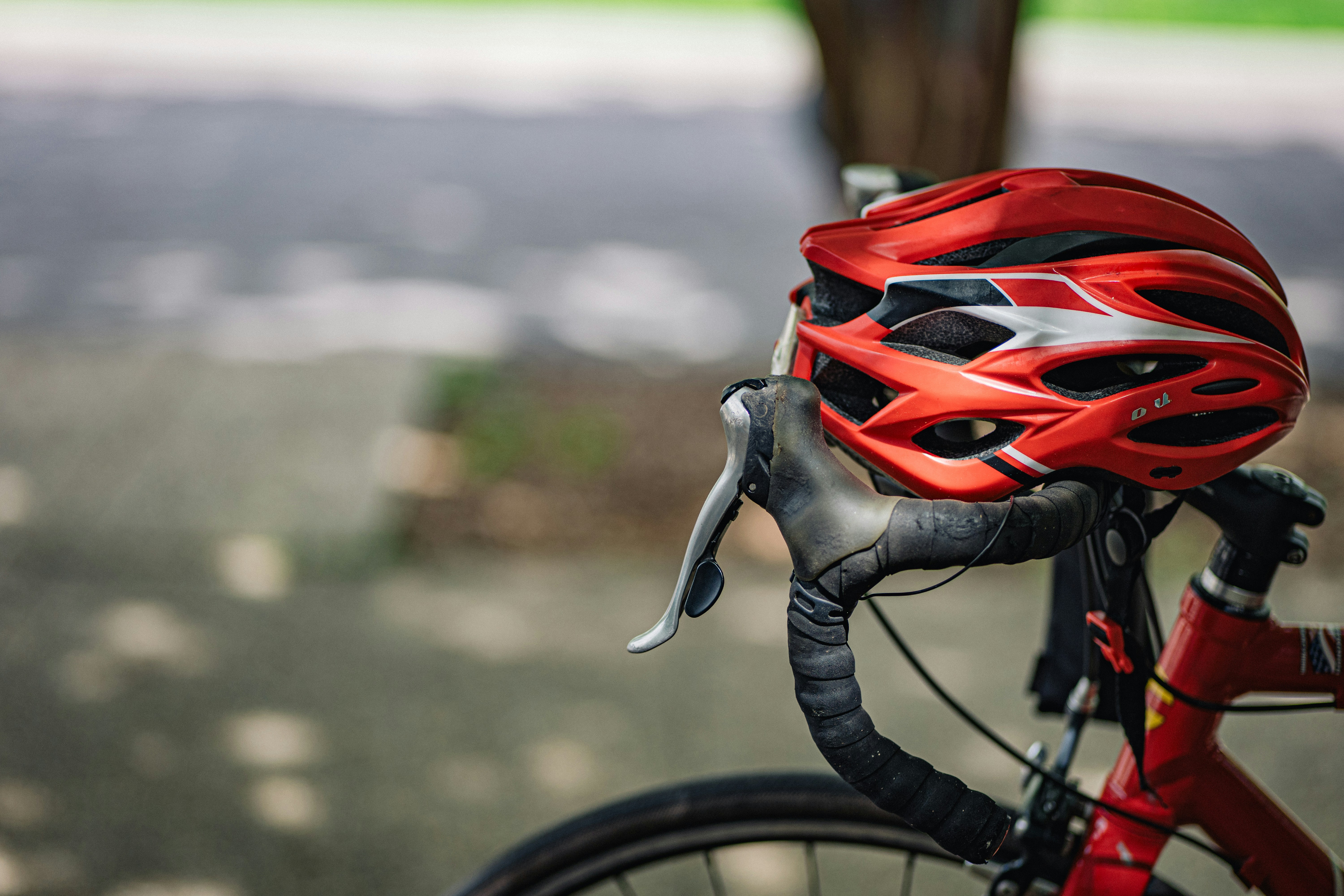 A red bicycle helmet rests on handlebars.