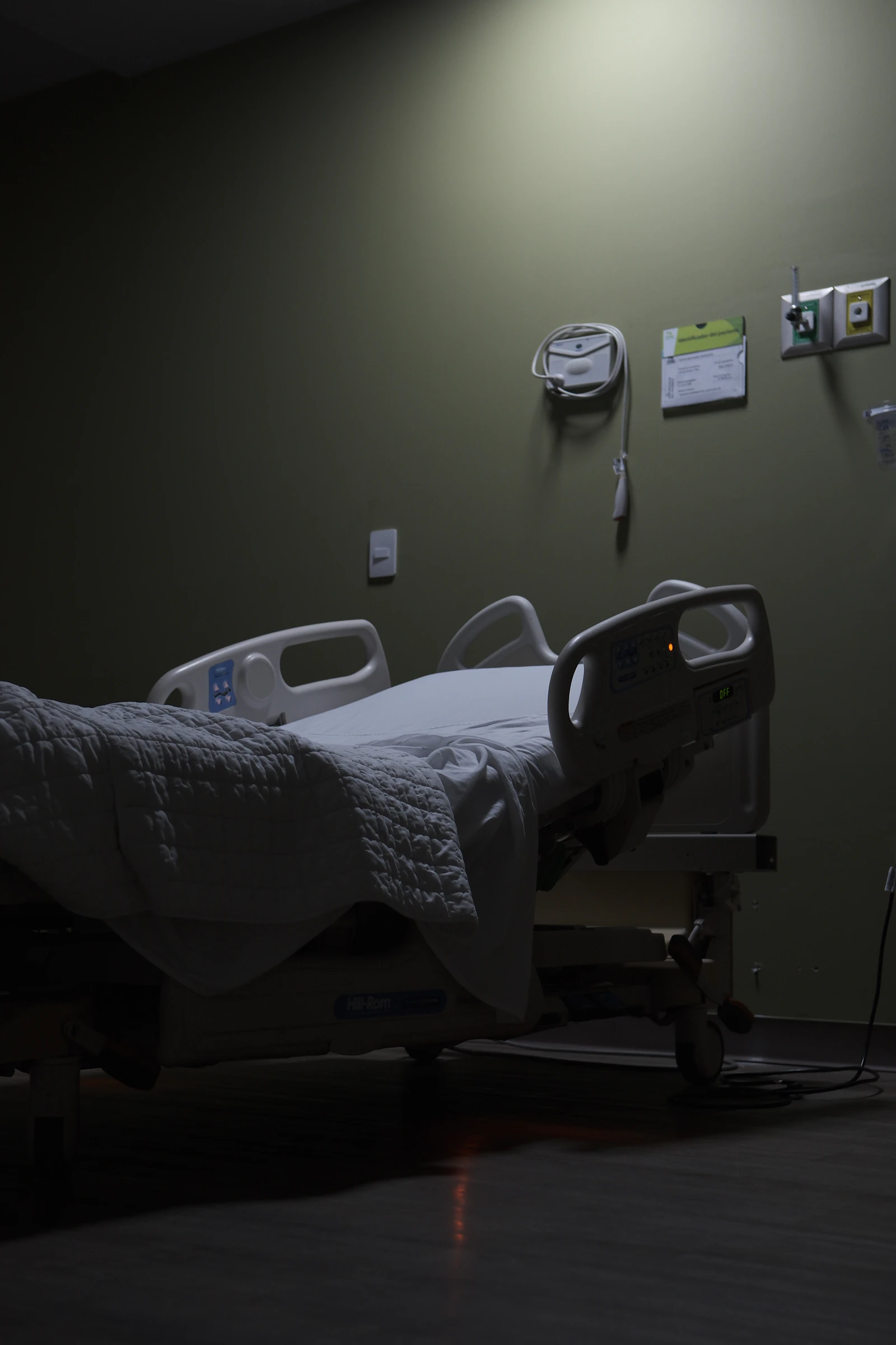 An empty hospital bed in a dimly lit room