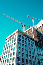 Construction cranes work on a building's exterior.