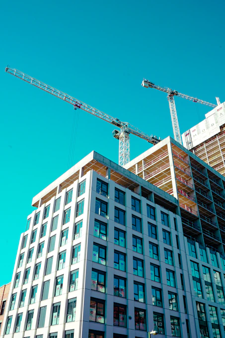 Construction cranes work on a building's exterior.