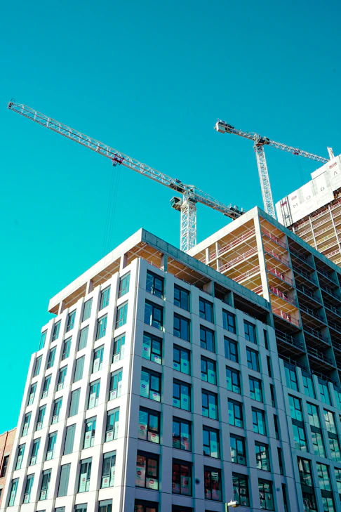Construction cranes work on a building's exterior.