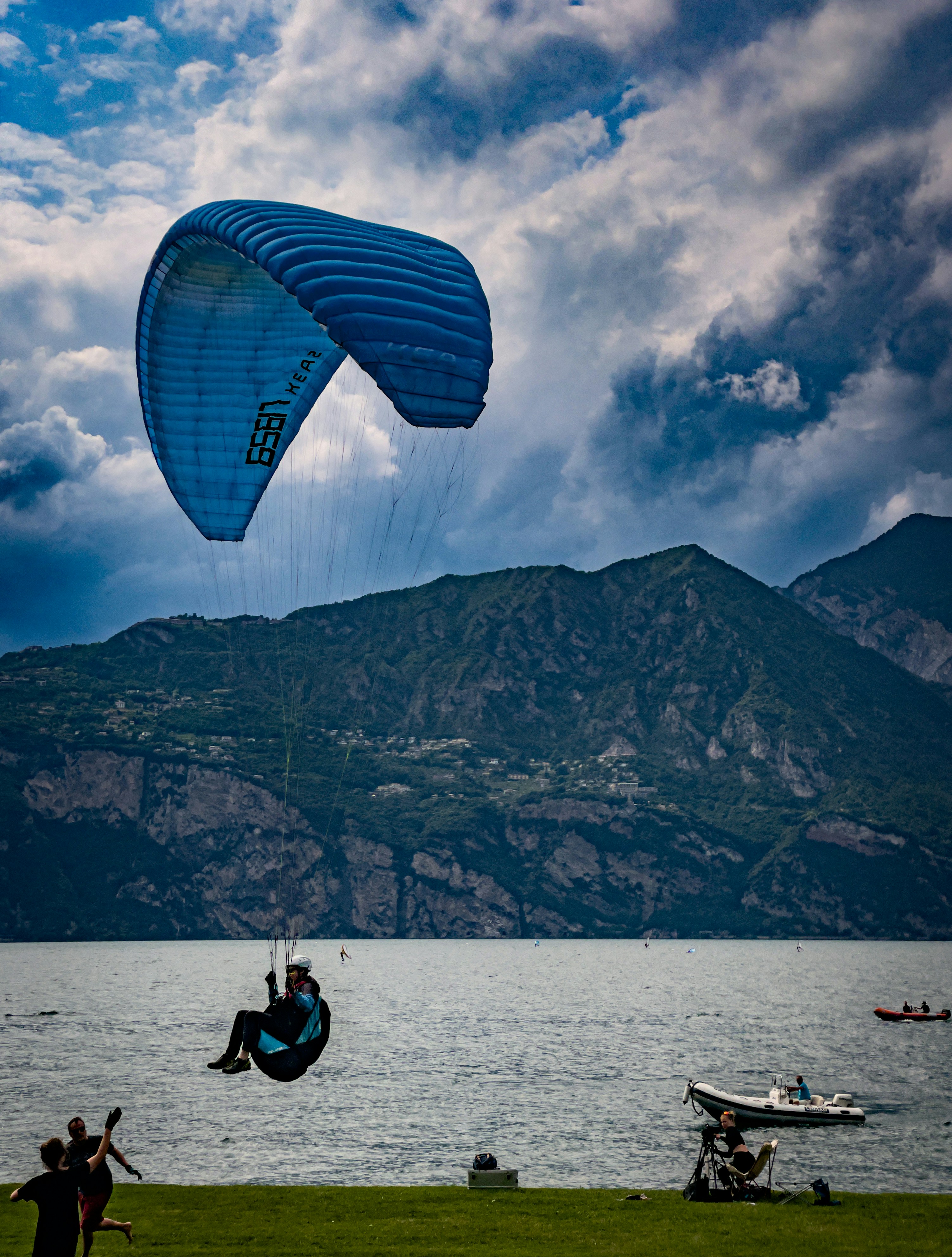 A paraglider soars over water and mountains.