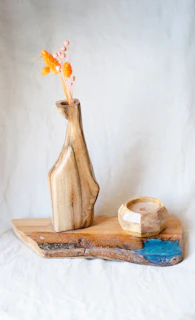 Wooden vase and decor with flowers on a board.