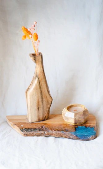 Wooden vase and decor with flowers on a board.