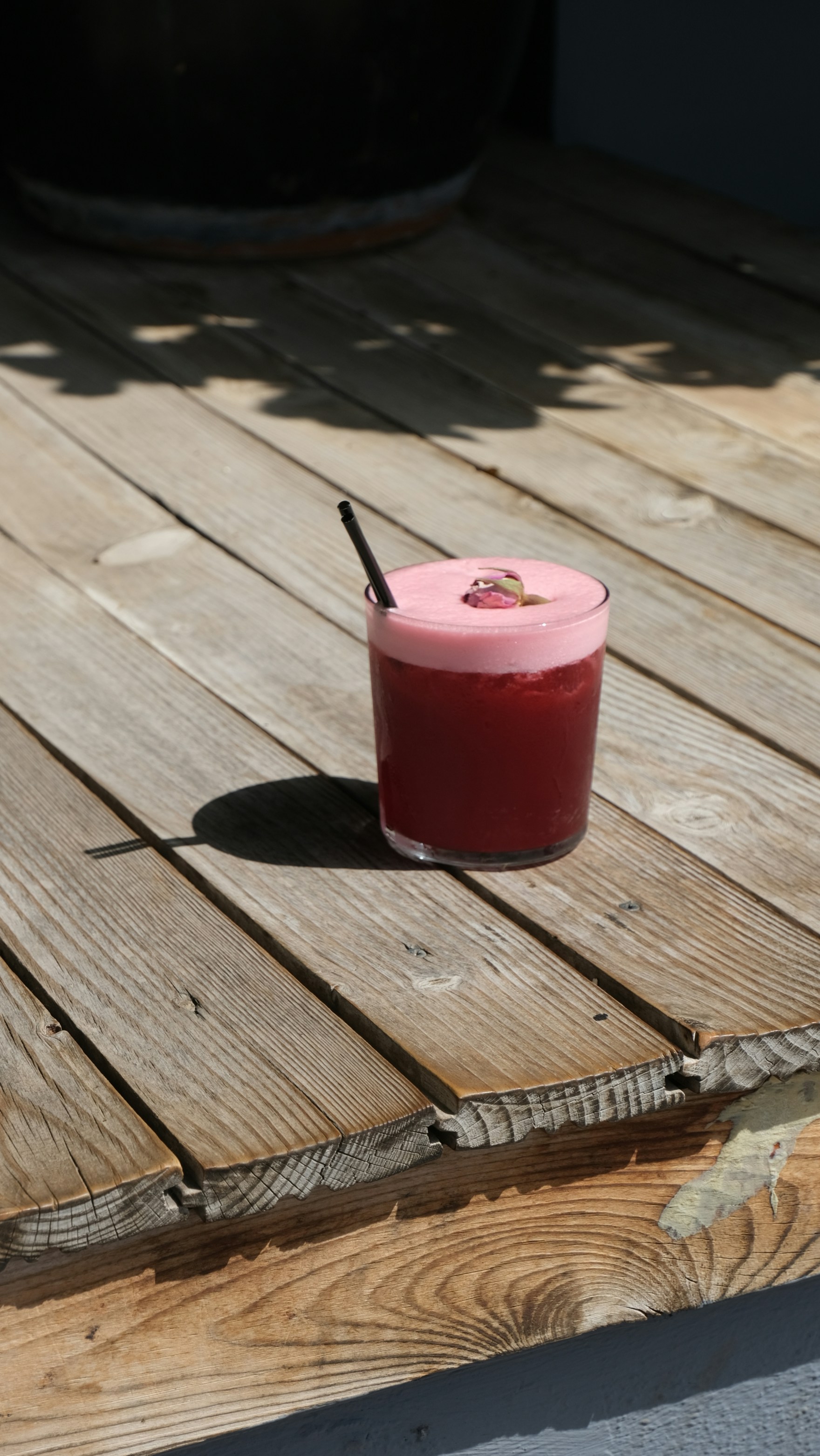 Un cóctel rojo con espuma y una pajita.