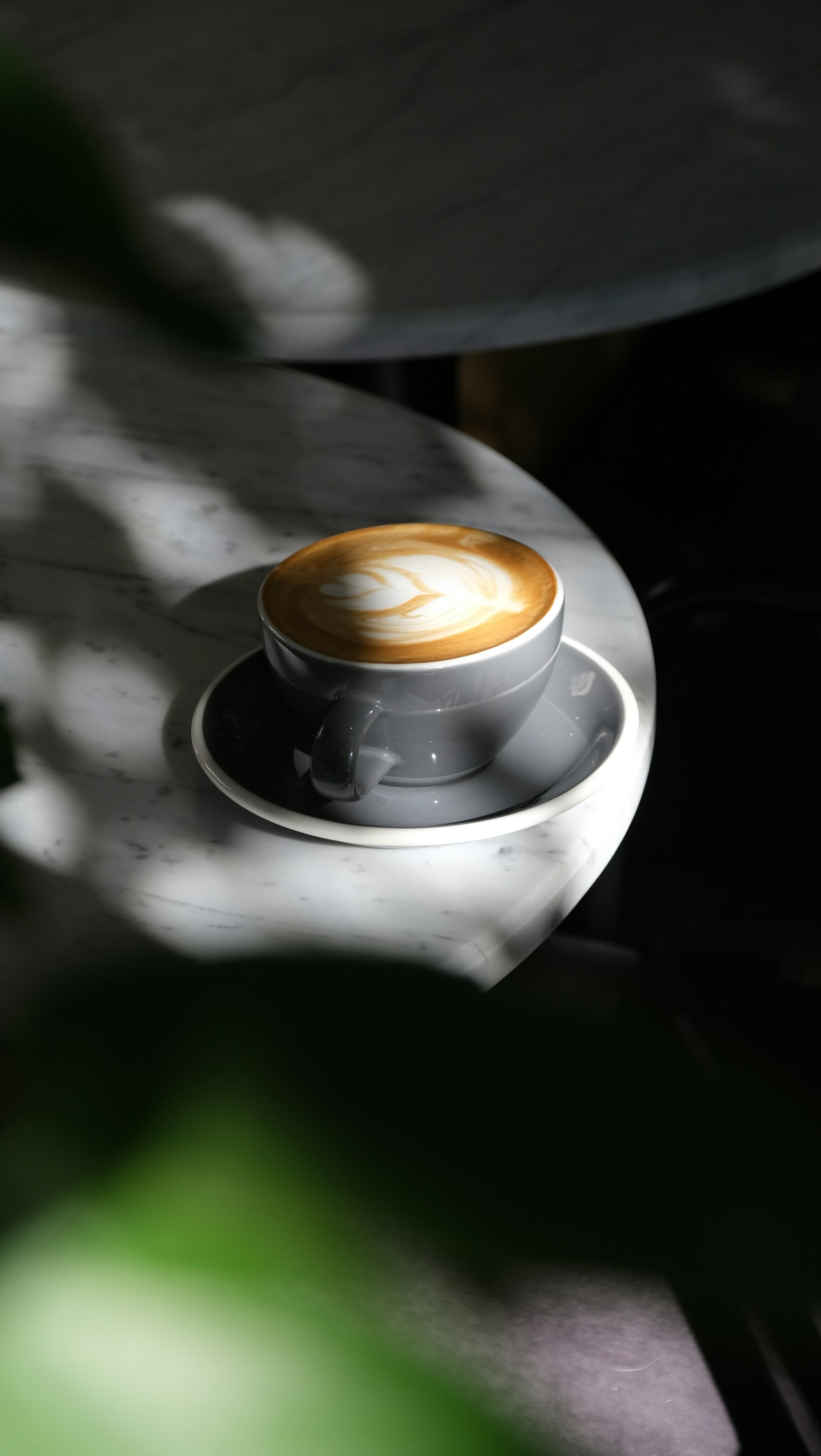 A latte art coffee sits on a marble table.