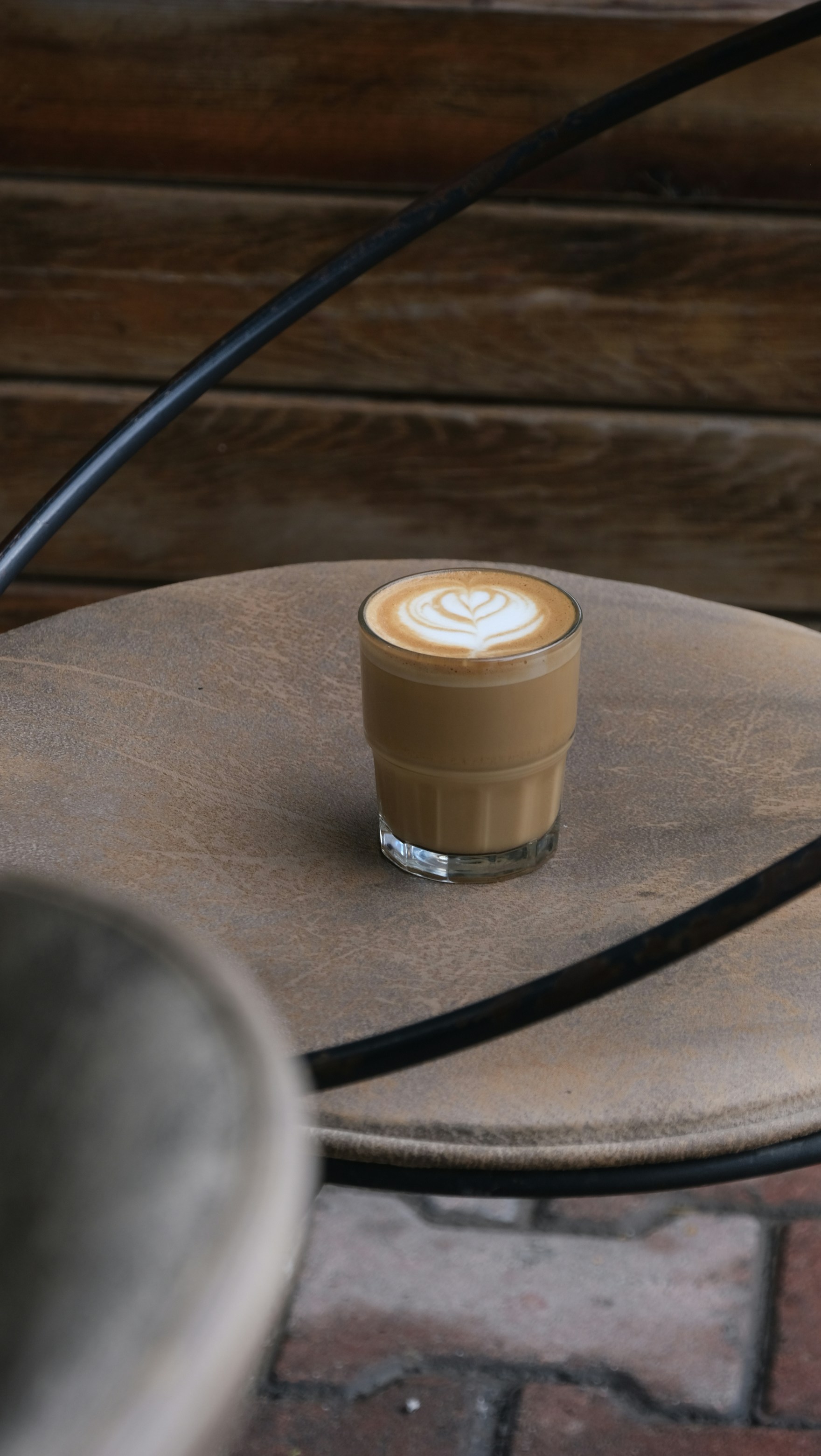 Latte with latte art sits on a round table.