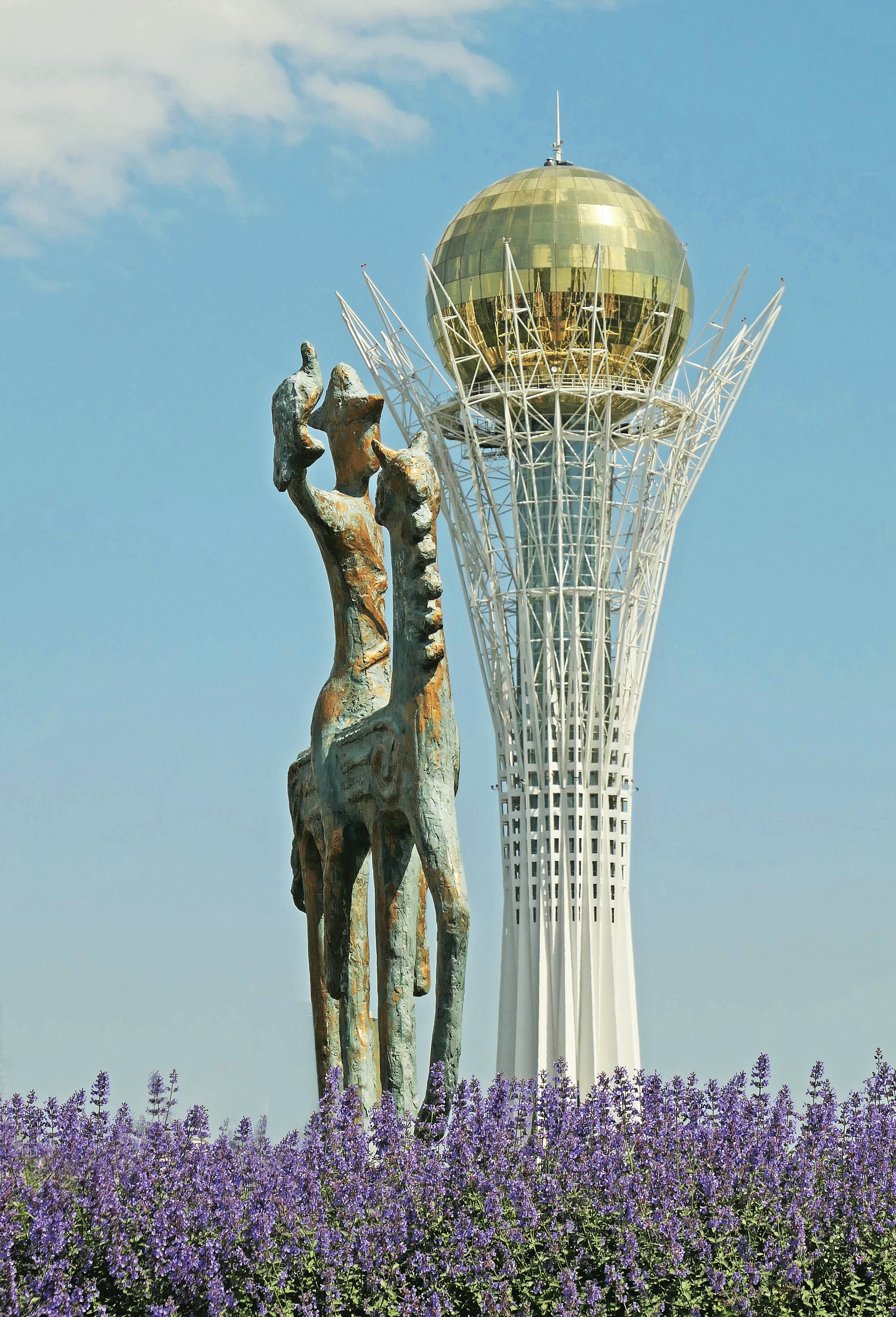 Monument and a tower rise against a blue sky.