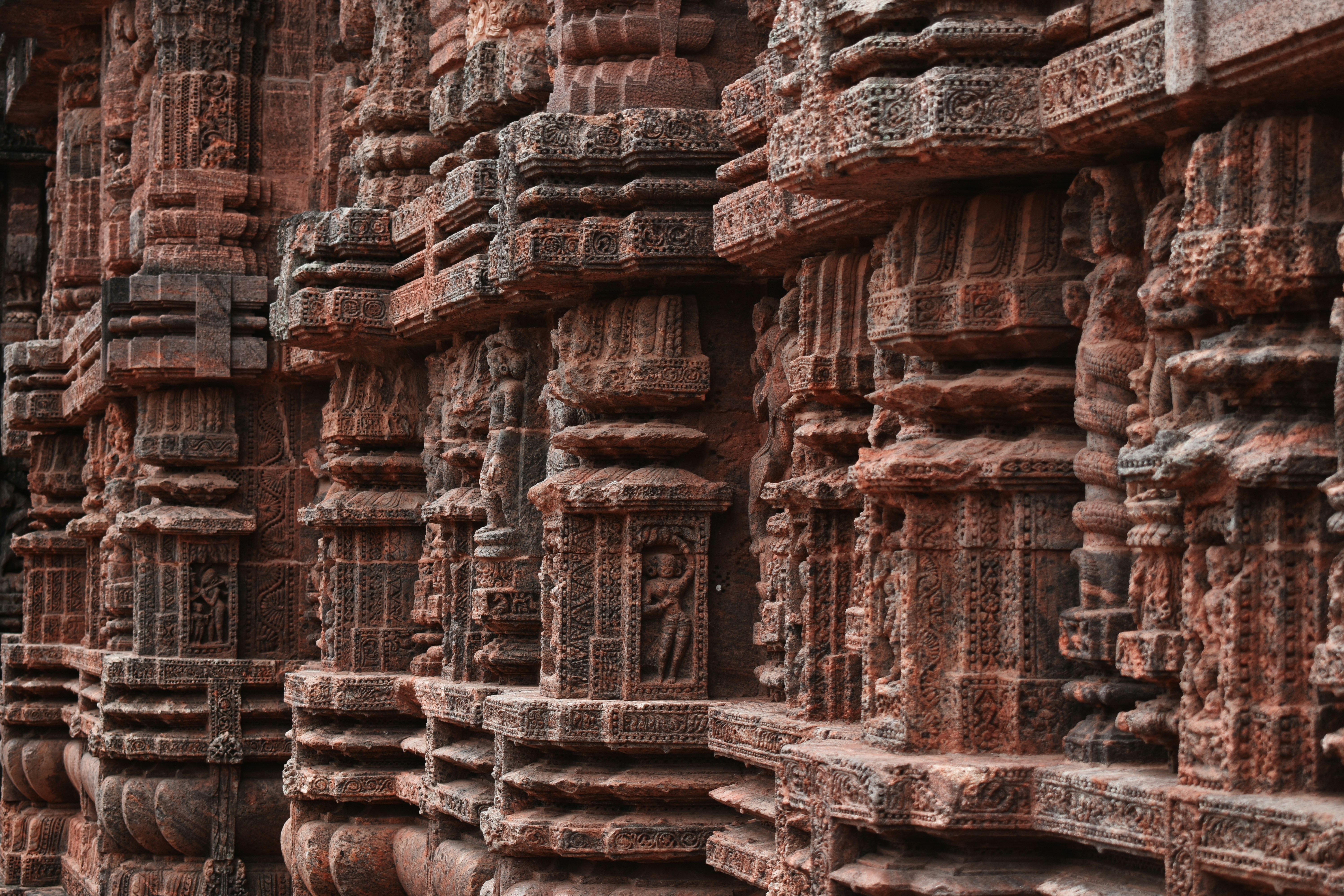 Aufwendige Schnitzereien schmücken die verwitterten Säulen eines Tempels.
