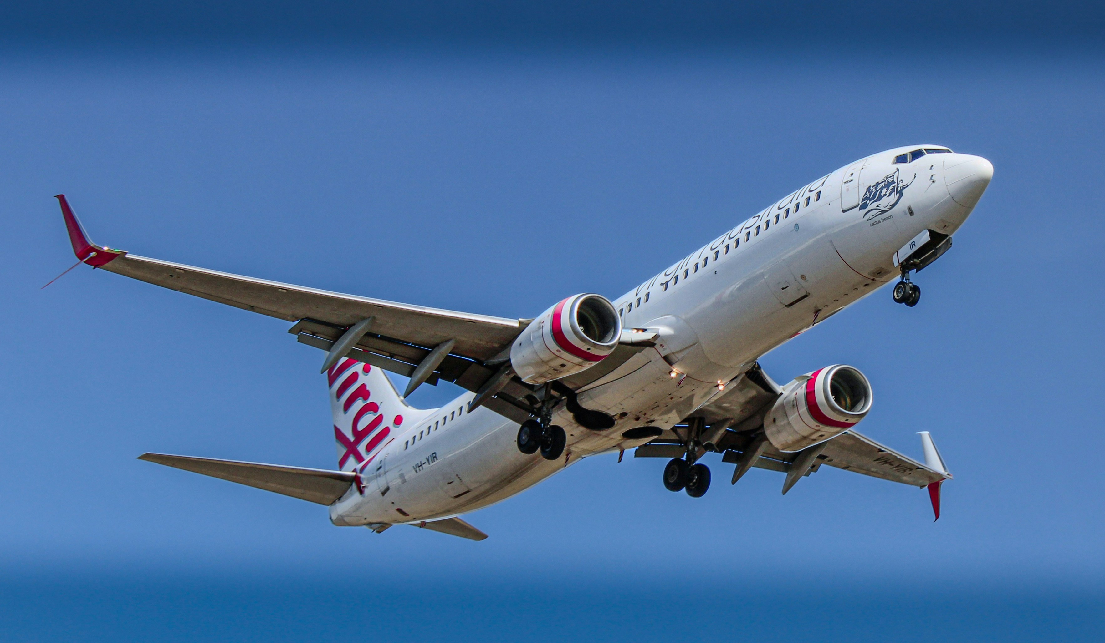 A virgin australia plane is soaring in the sky.