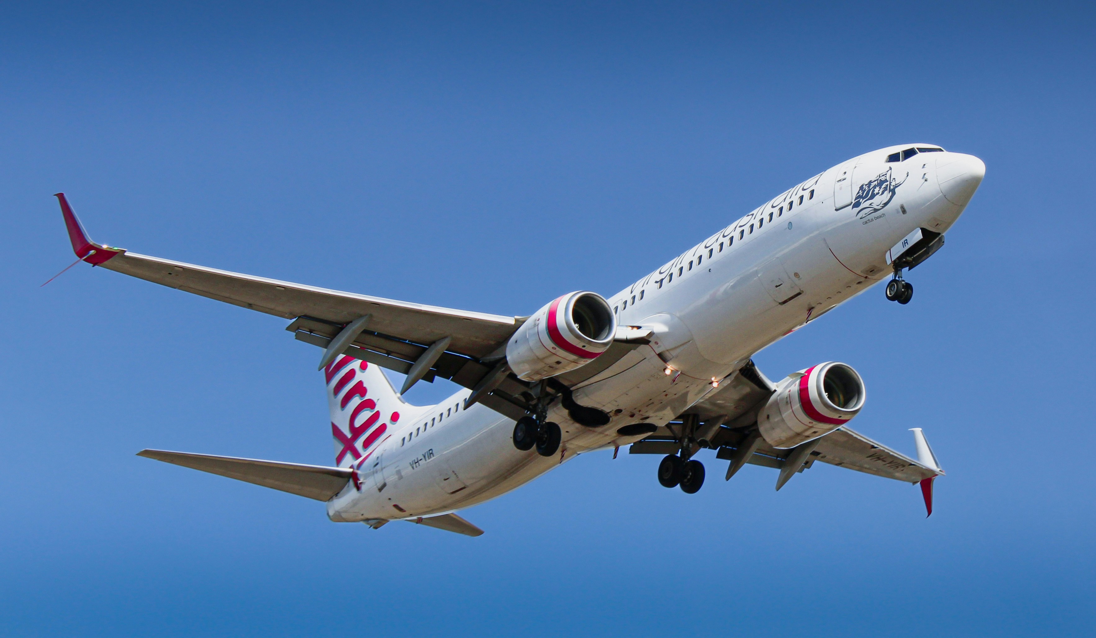 An airplane soars through a clear, blue sky.