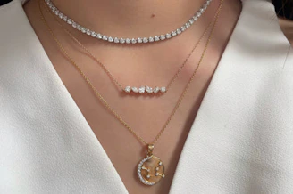Here's a caption: three necklaces adorned on a neck.