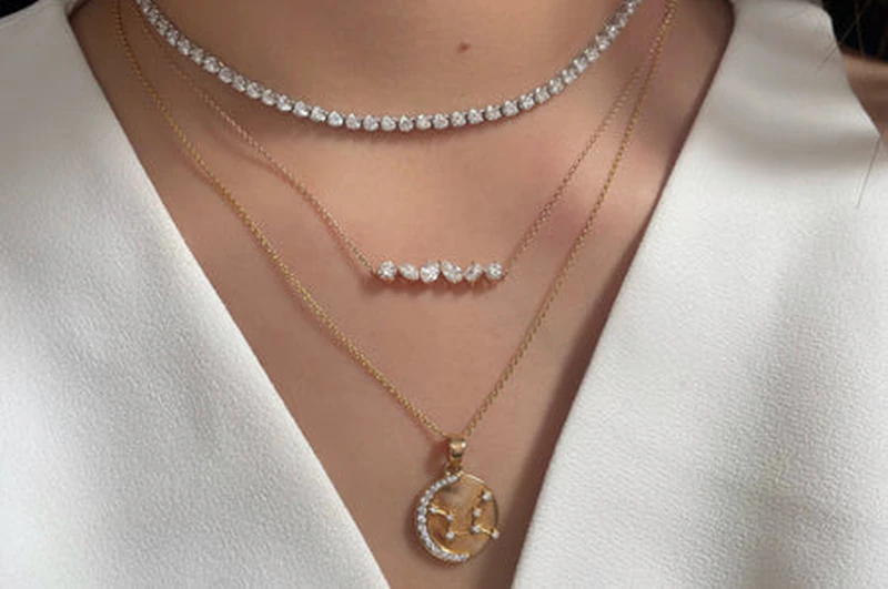 A tennis choker layered with a bar necklace and a medallion