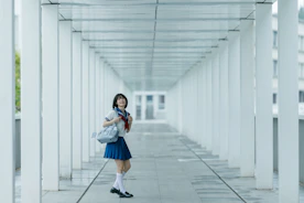 Schoolgirl poses in a white hallway.