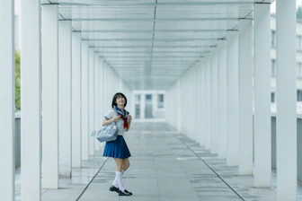 Schoolgirl poses in a white hallway.