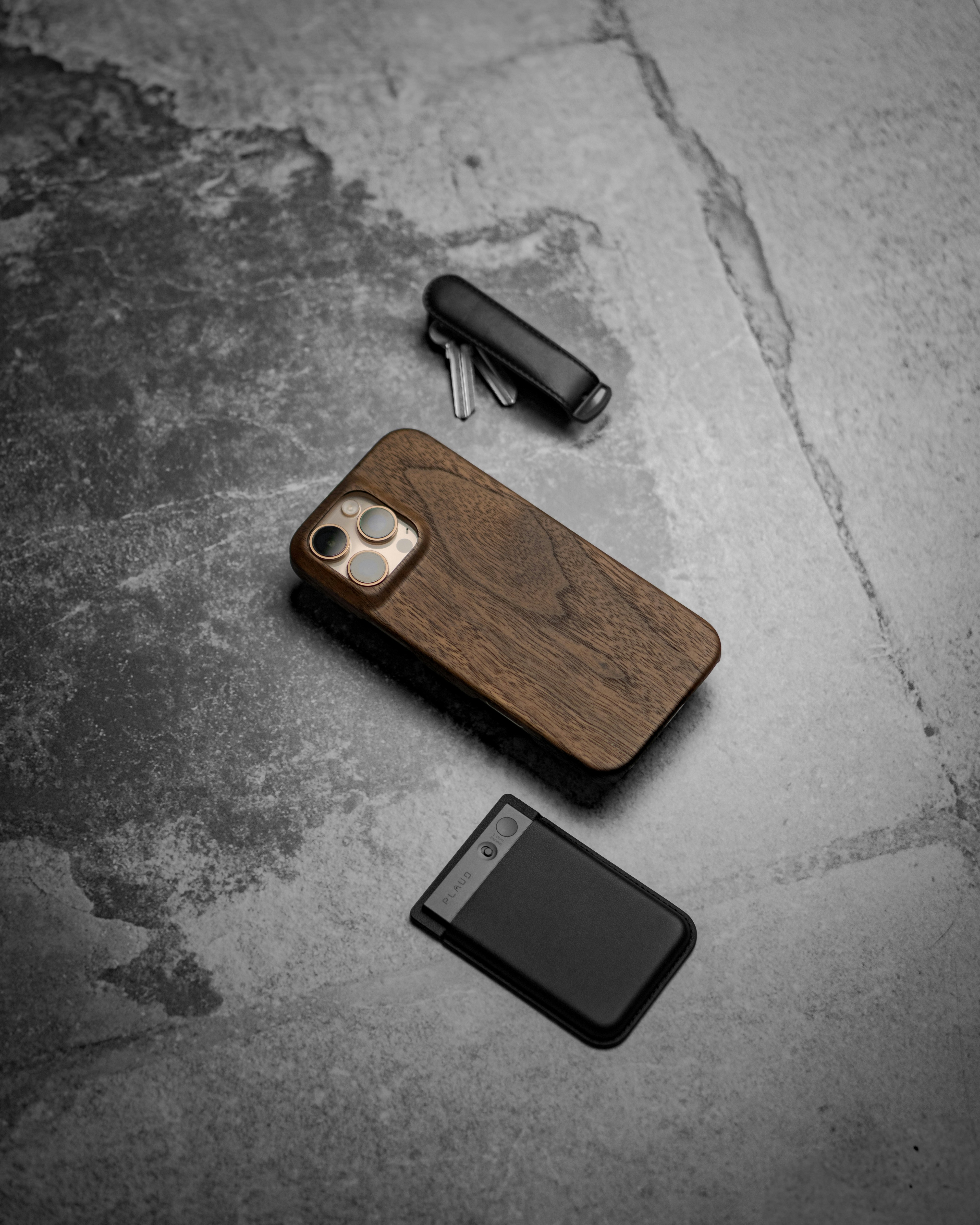 Telefone, chaves e carteira em uma superfície texturizada.