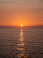 The sun sets over the calm ocean waters.