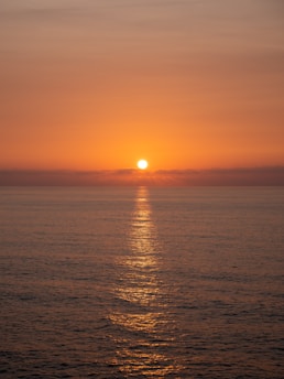 The sun sets over the calm ocean waters.