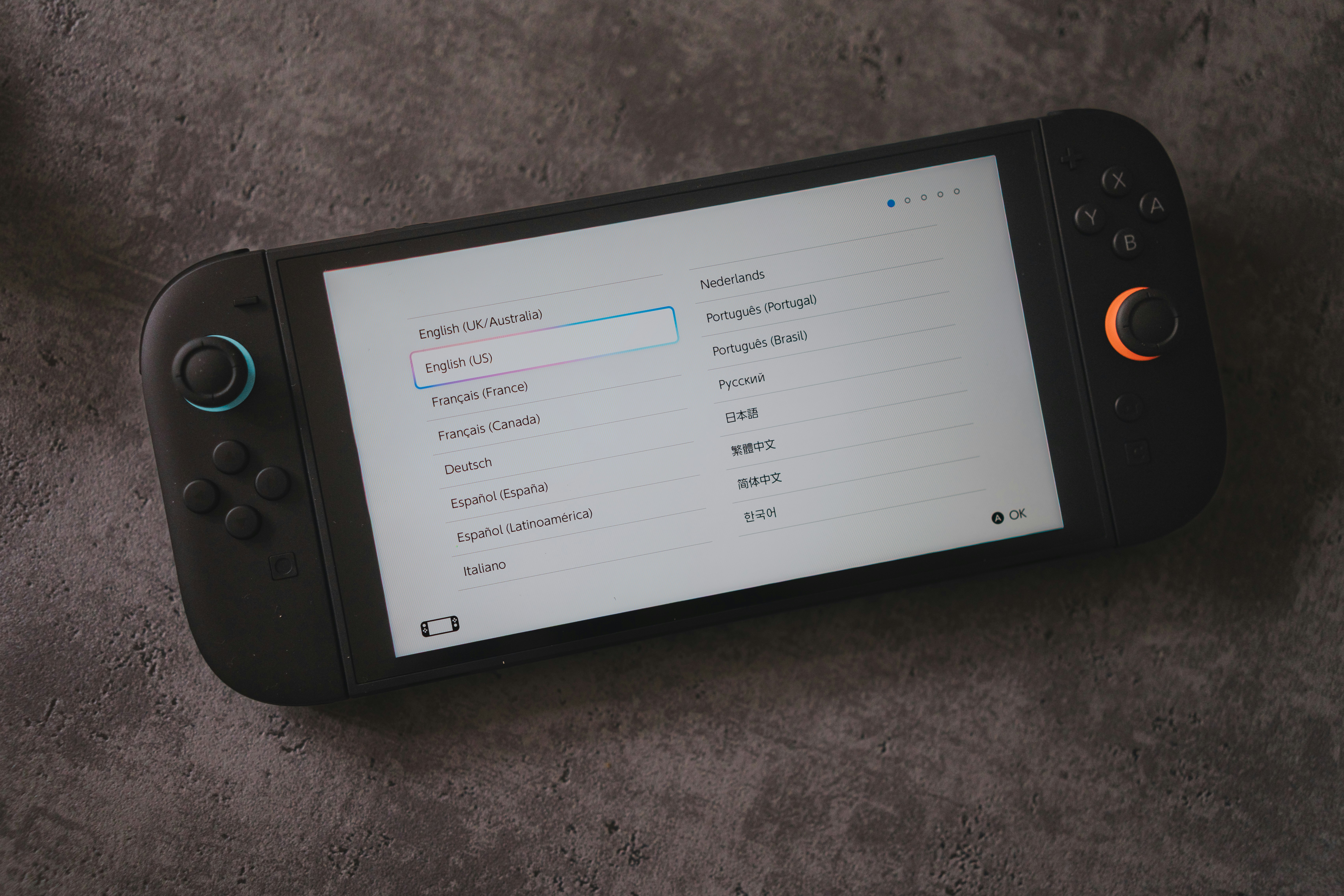 A handheld console displays language options.