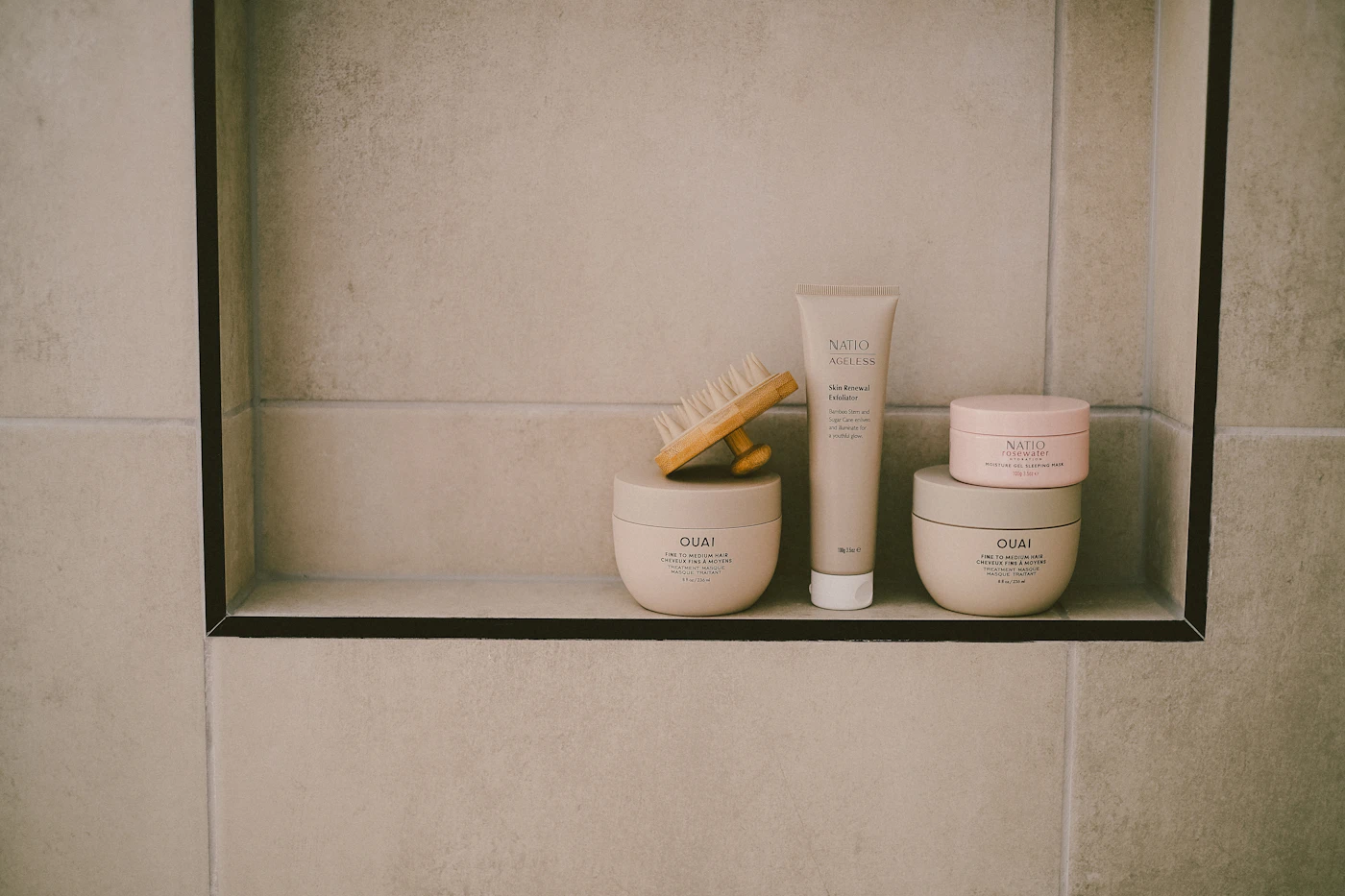Personal care products arranged on a tiled bathroom shelf