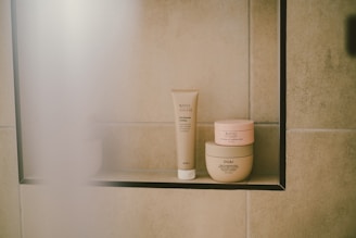 Skincare products sit on a shelf in a shower.
